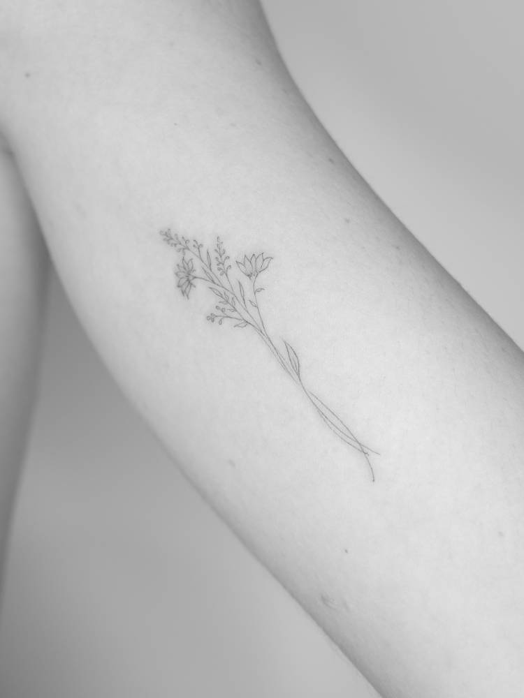 Flower bouquet tattoo in fine line style located on the inner arm.
