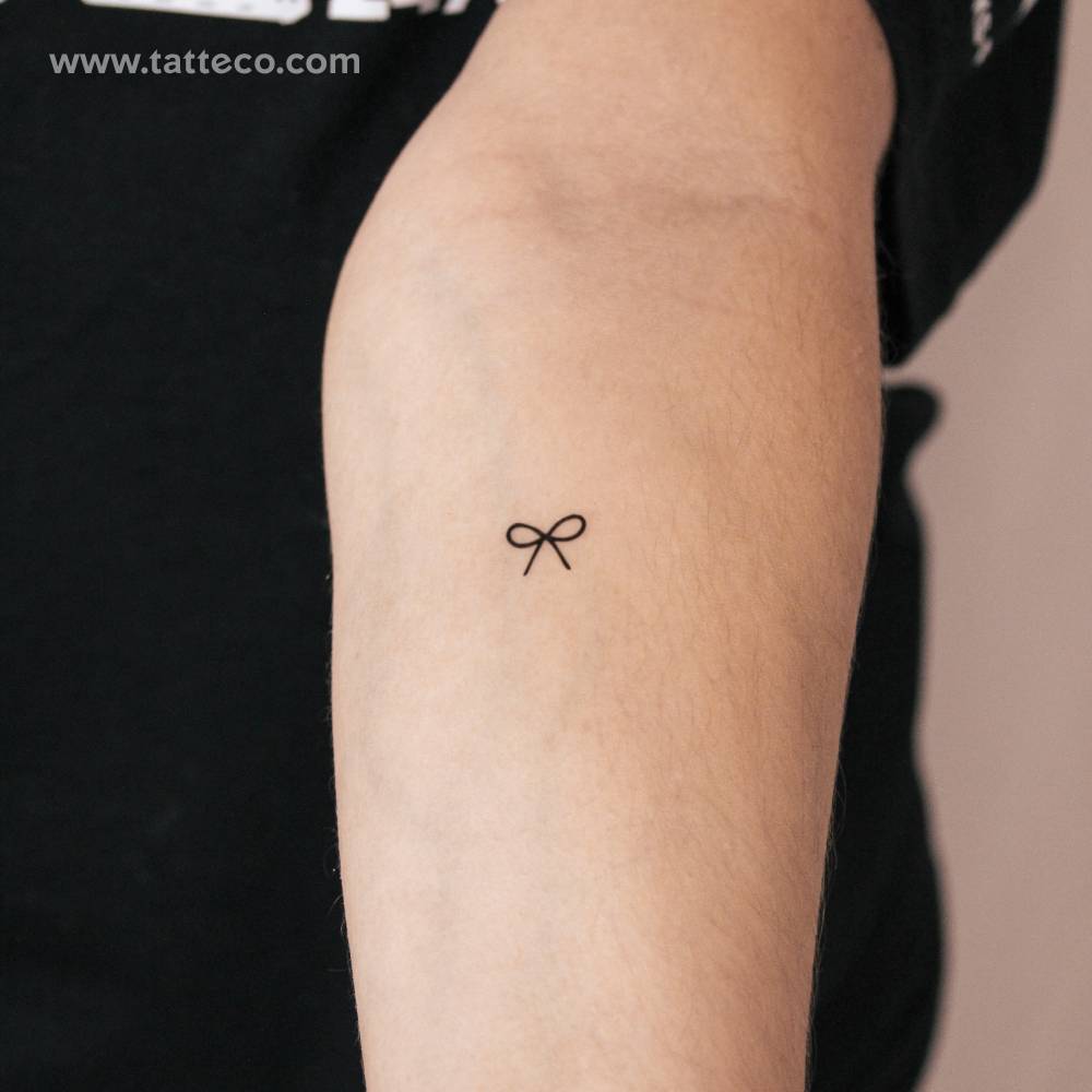Minimalist bow semi-permanent tattoo located on the inner forearm.