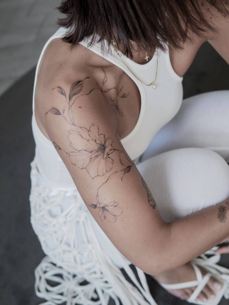 Illustrative style magnolia tattoo located on the upper arm.