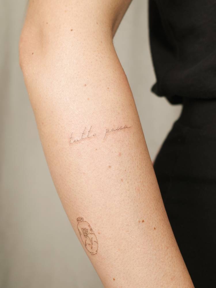 Handwritten font "tutto passa" tattoo located on the forearm.