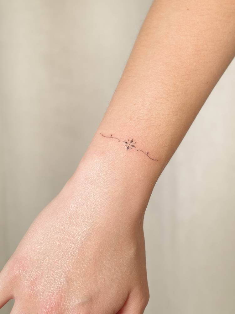 Minimalistic ornamental tattoo located on the wrist.
