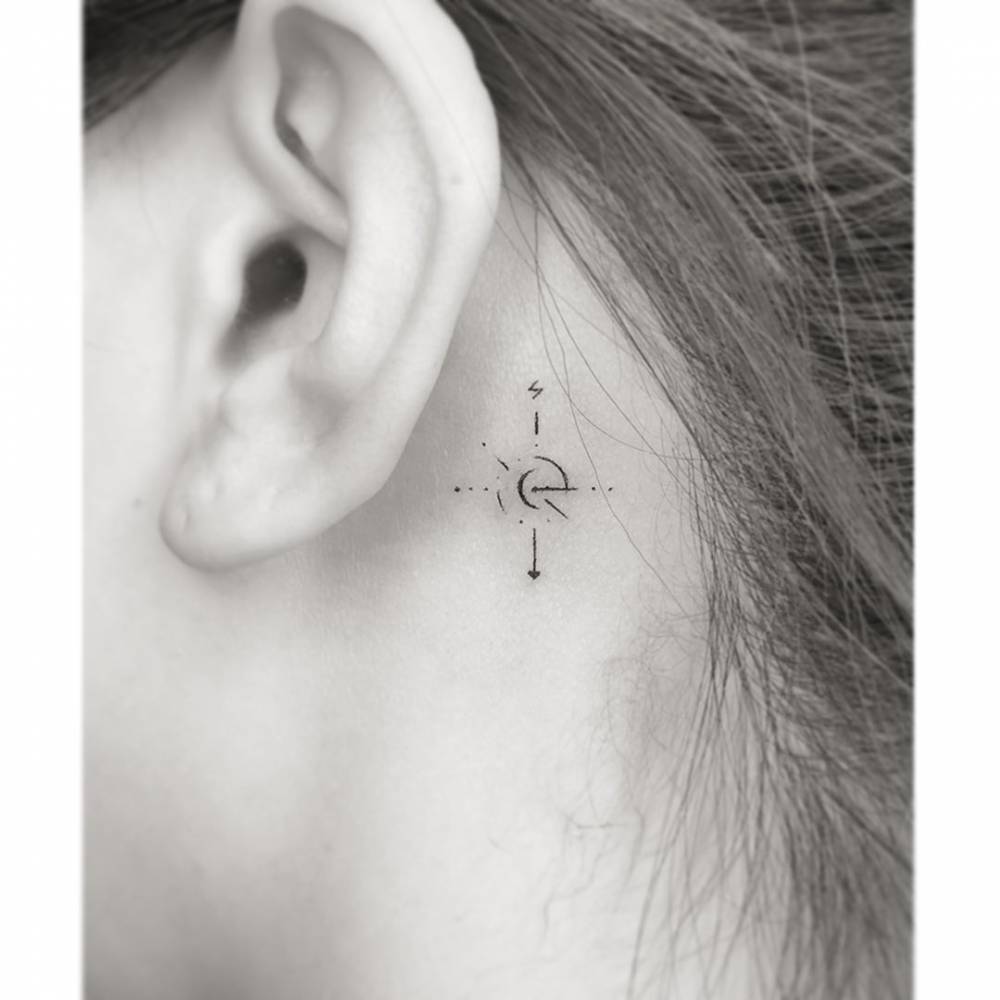 Compass rose tattoo in minimalistic style placed behind the ear.