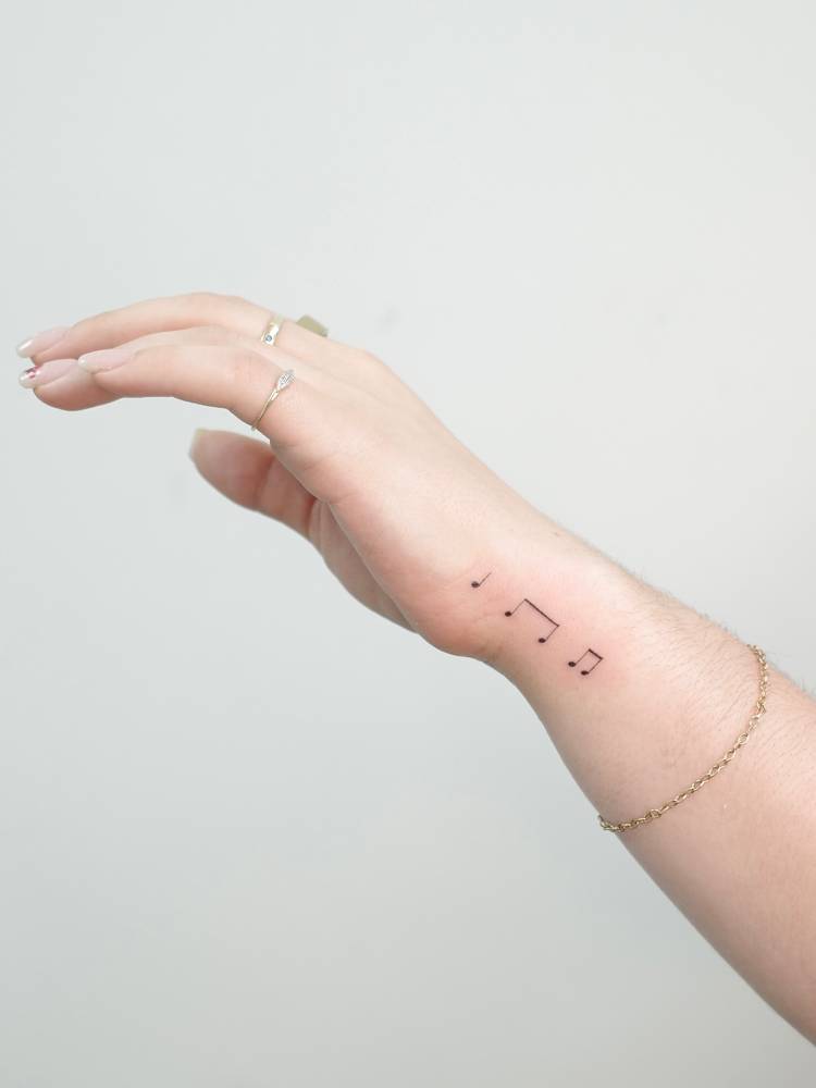 Music notes tattooed on the wrist, minimalistic style.