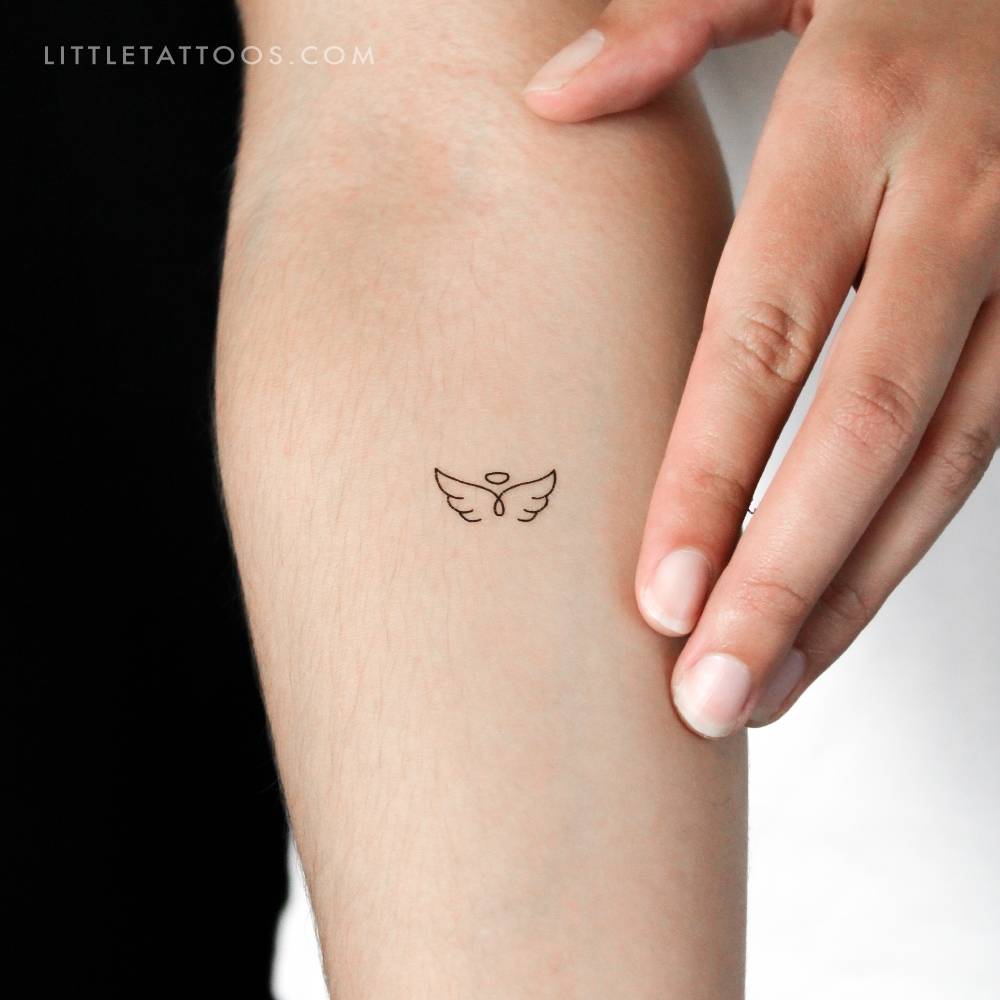 Angel wings and halo temporary tattoo located on the inner forearm.