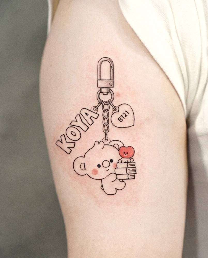 Cartoon style BT21 "Koya" keychain tattoo located on the upper arm.