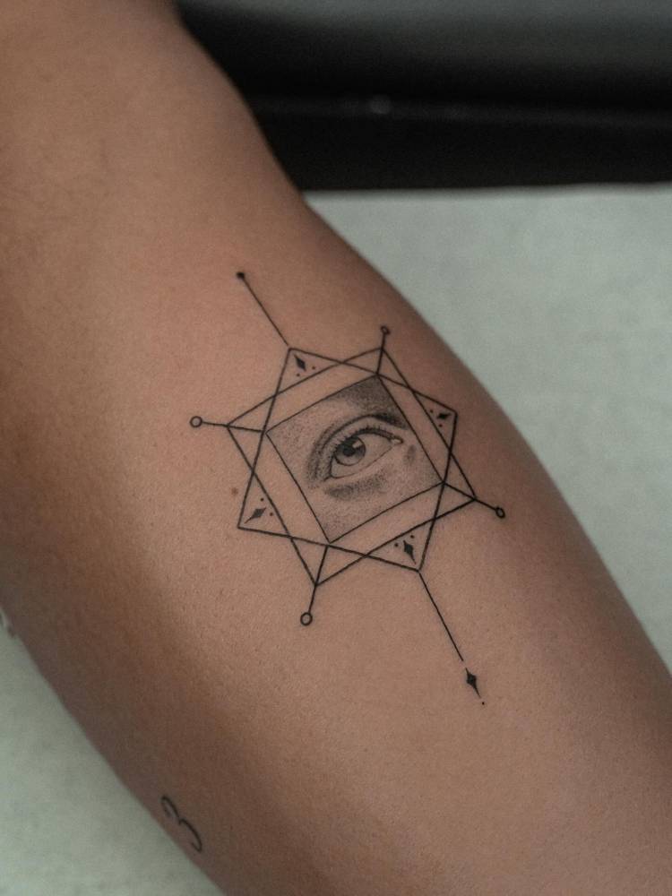 Geometric eye tattooed on the inner forearm.