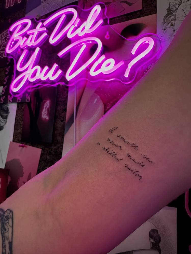 "A smooth sea never made a skilled sailor" lettering tattoo in handwritten font.