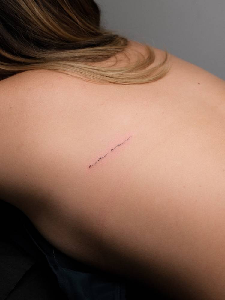 Handwritten font word "amour" tattooed on the back.