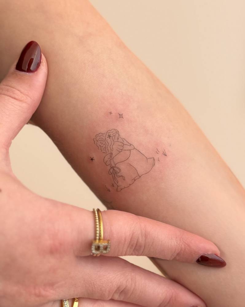 Hug tattoo in fine line style located on the inner forearm.