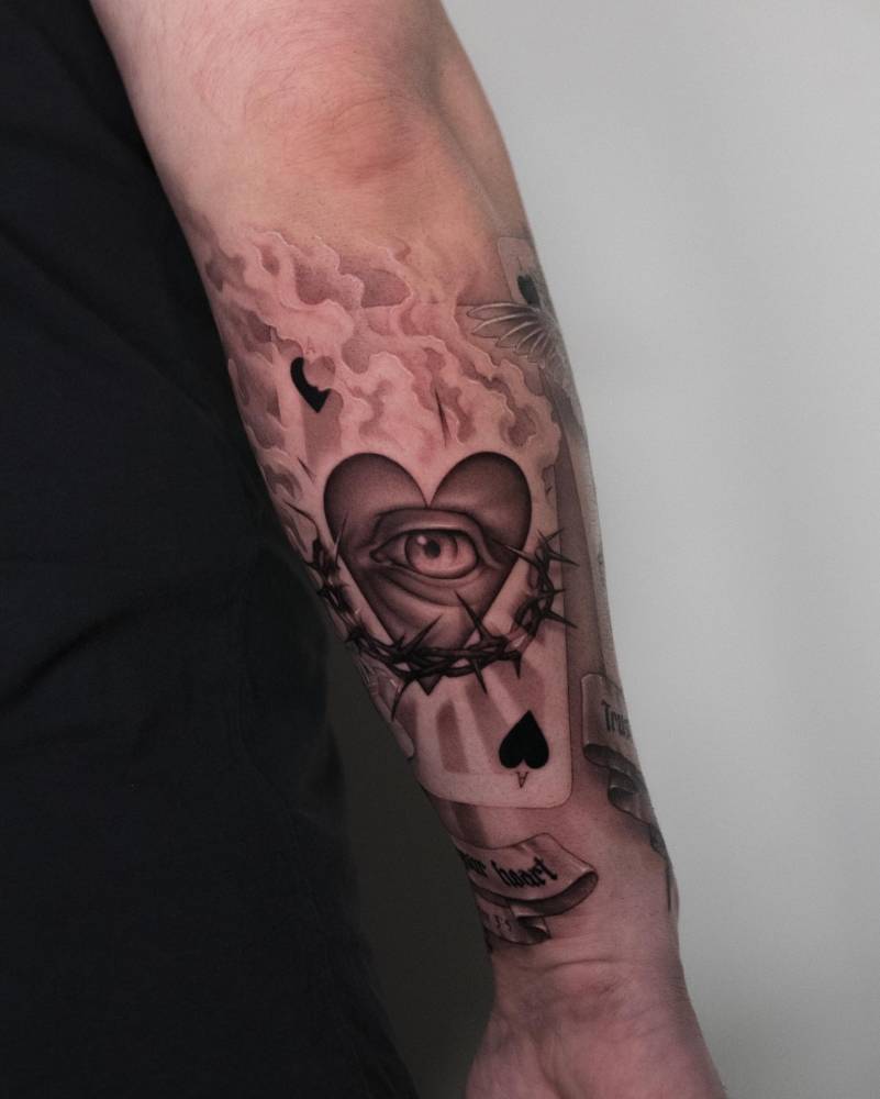 Sacred heart and ace of spades card tattooed on the forearm.