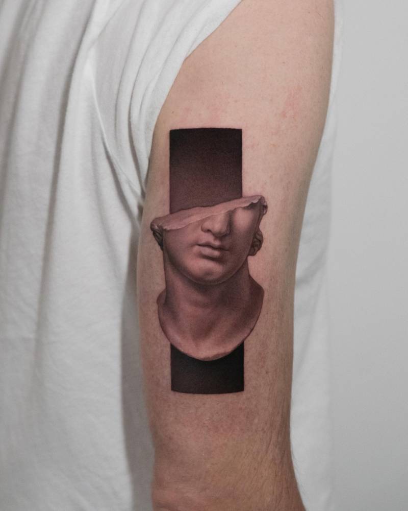Greek sculpture tattoo located on the tricep, micro-realistic style.