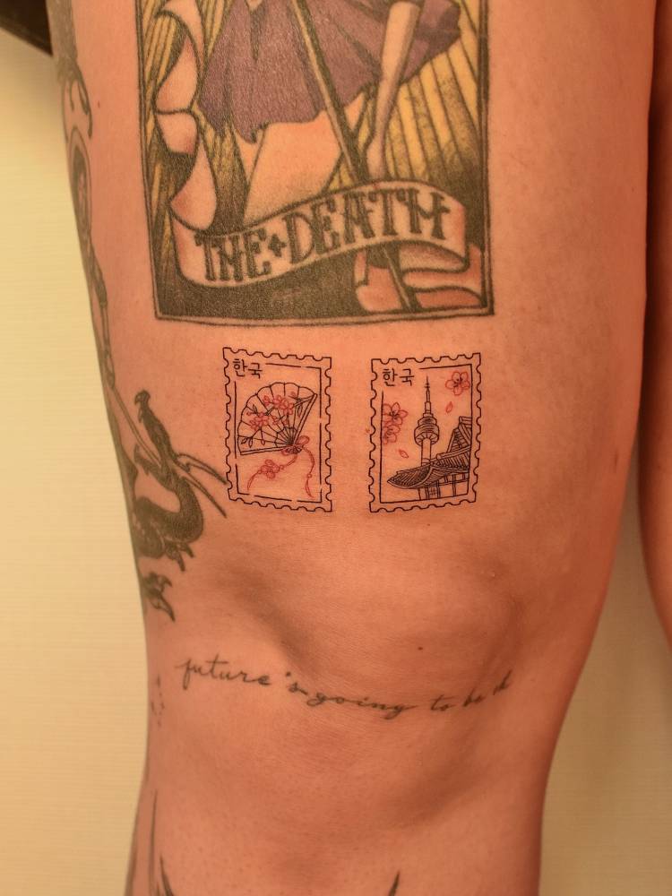 Korean stamps tattoo in fine line style located on the thigh.