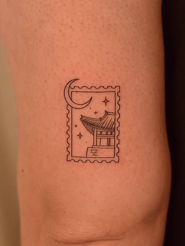 Pagoda stamp tattoo placed on the tricep, done in fine line style.
