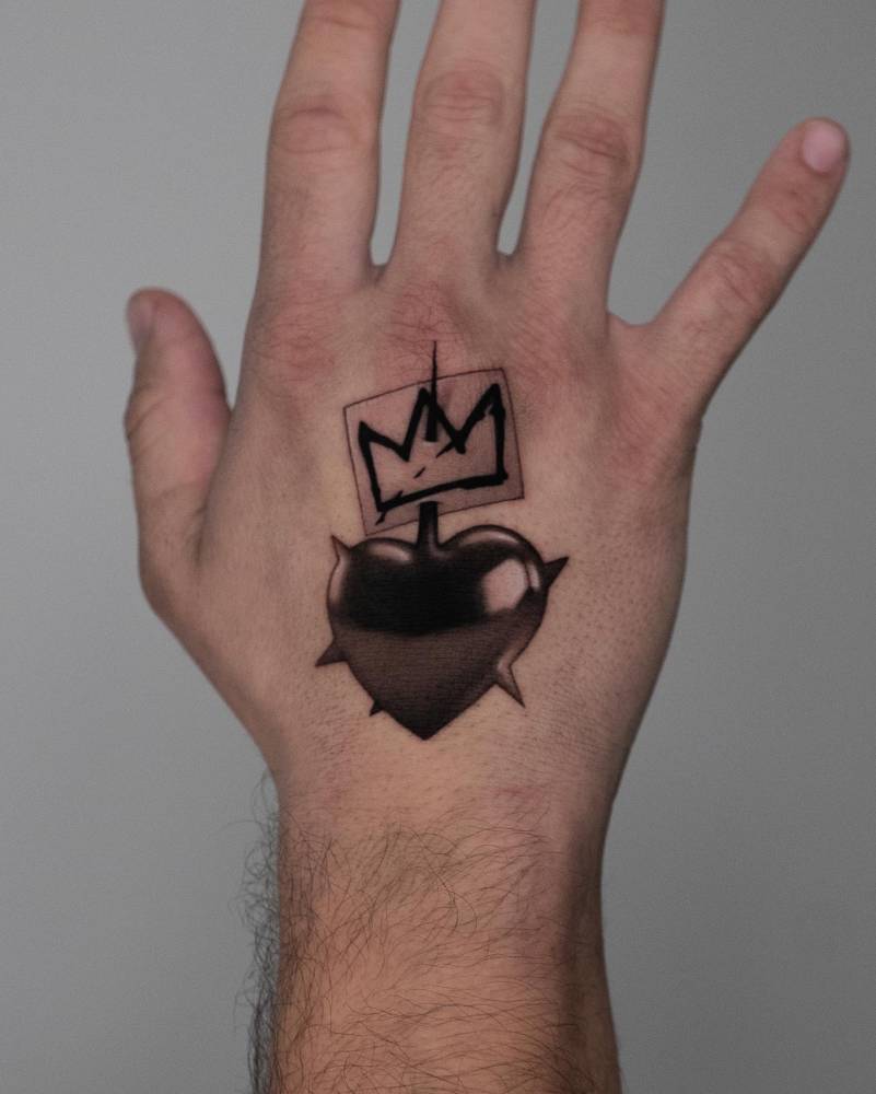 Jean-Michel Basquiat's crown and spikey heart tattooed on the hand.