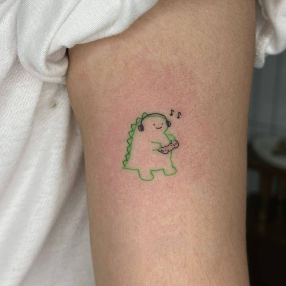 Gamer dinosaur tattoo hand poked on the bicep.