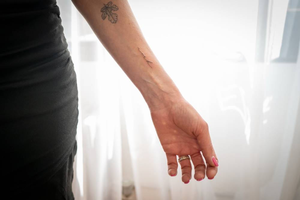 Initials tattoo in handwritten font placed on the wrist.