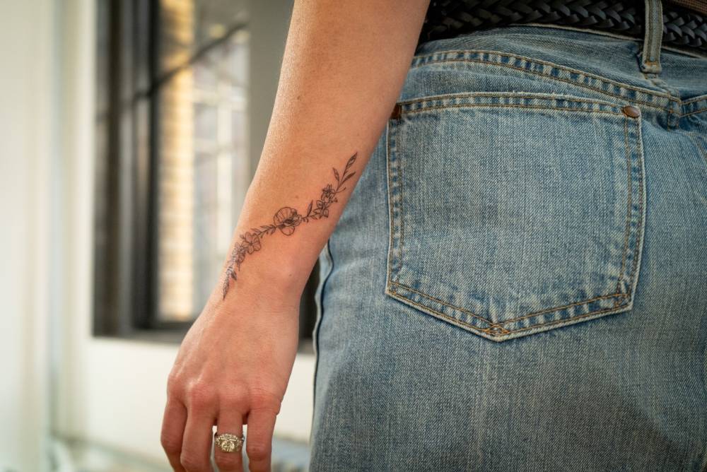 Floral design in illustrative style tattooed on the wrist.