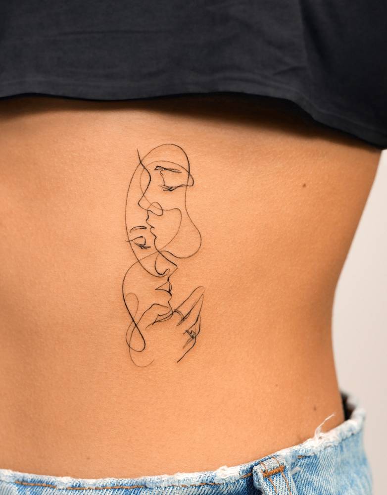Continuous line kiss tattoo located on the rib.