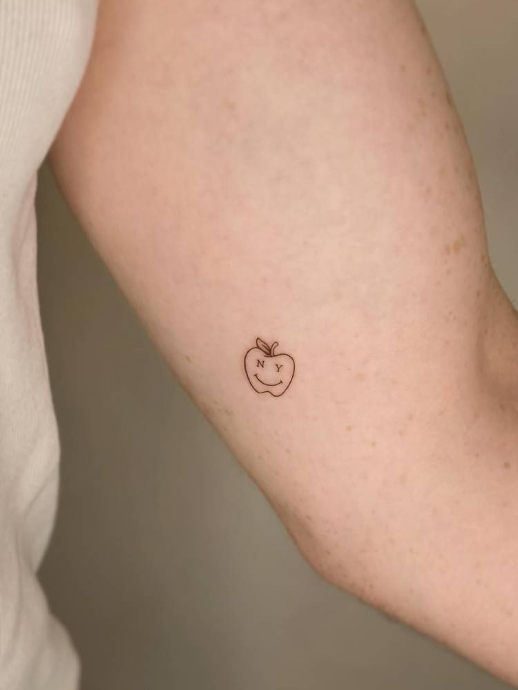 NY apple tattooed on the inner arm, minimalistic style.