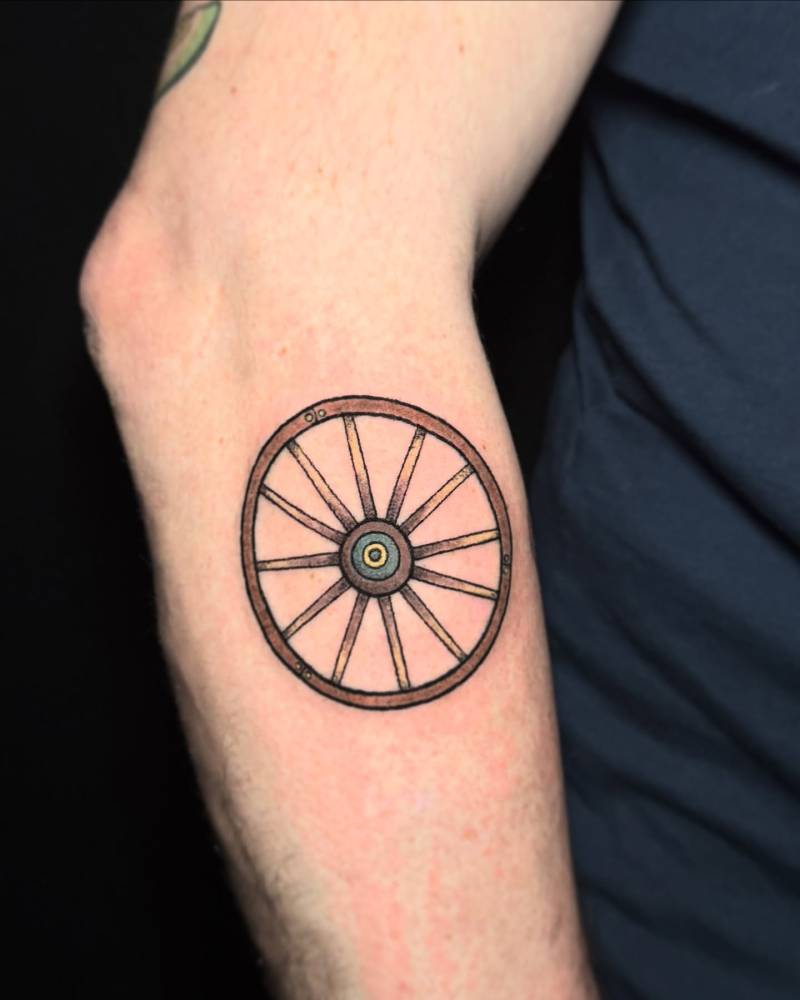 Hand poked wheel tattoo located on the forearm.