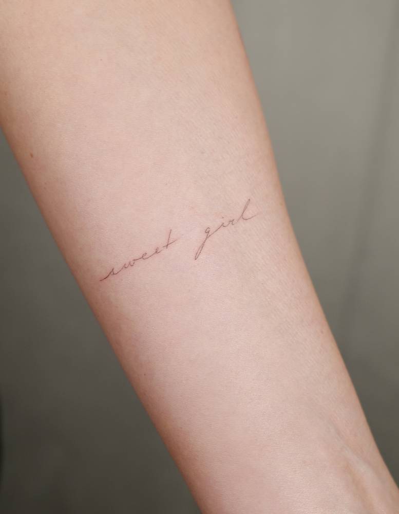 "Sweet girl" lettering tattoo handwritten on the inner forearm.