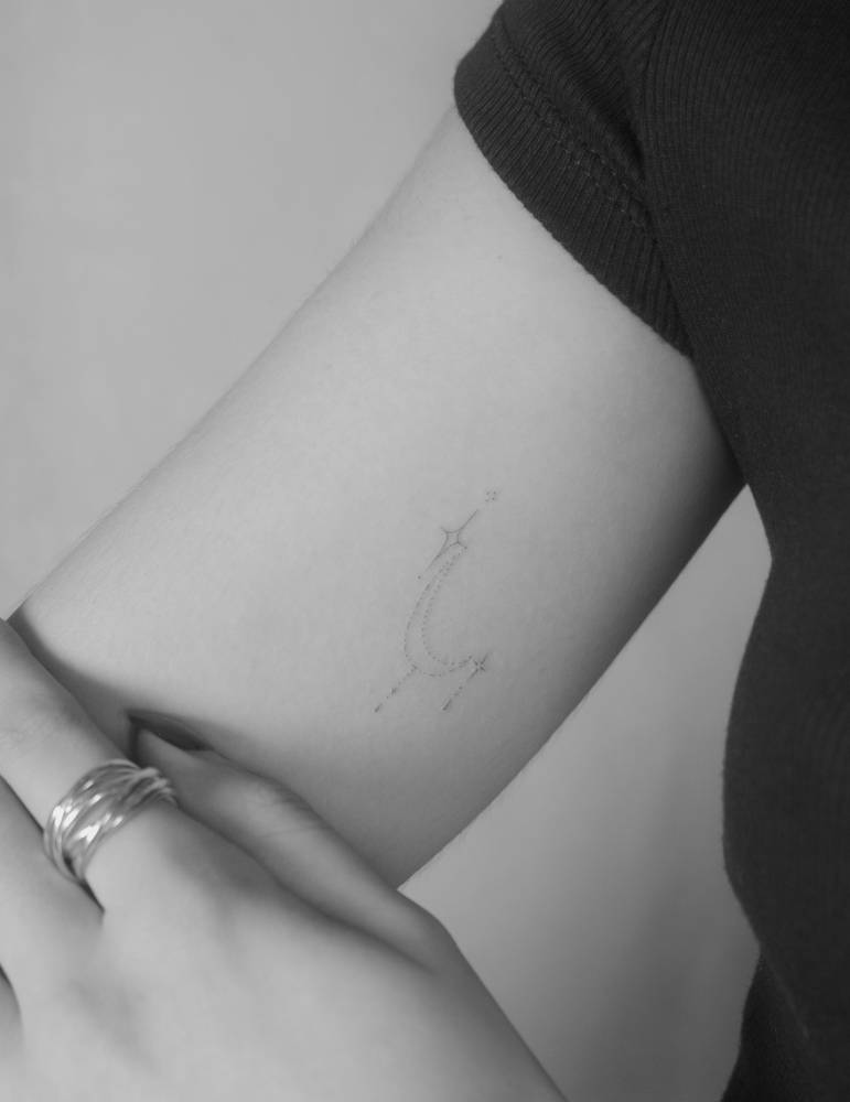 Ornamental stars tattooed on the inner arm, fine line style.