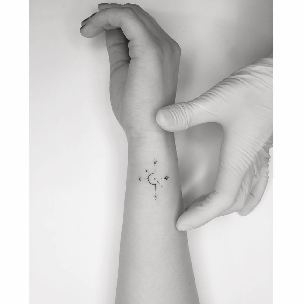 Compass rose tattoo in minimalistic style located on the wrist.