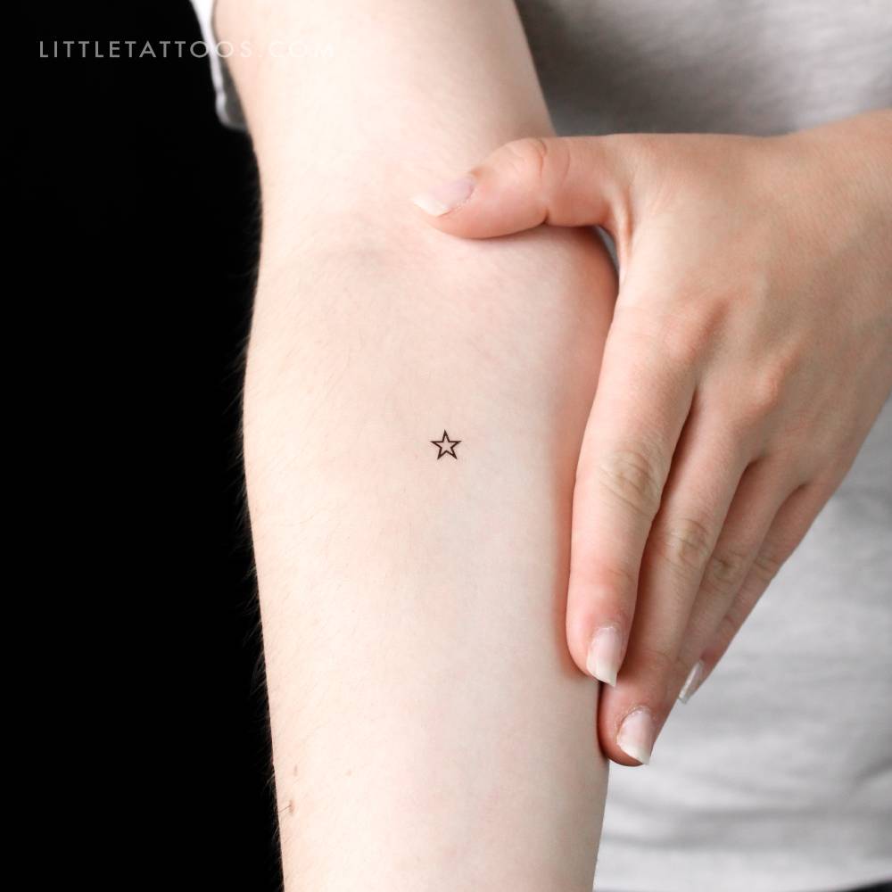 Tiny minimalist star outline temporary tattoo located on the inner forearm.