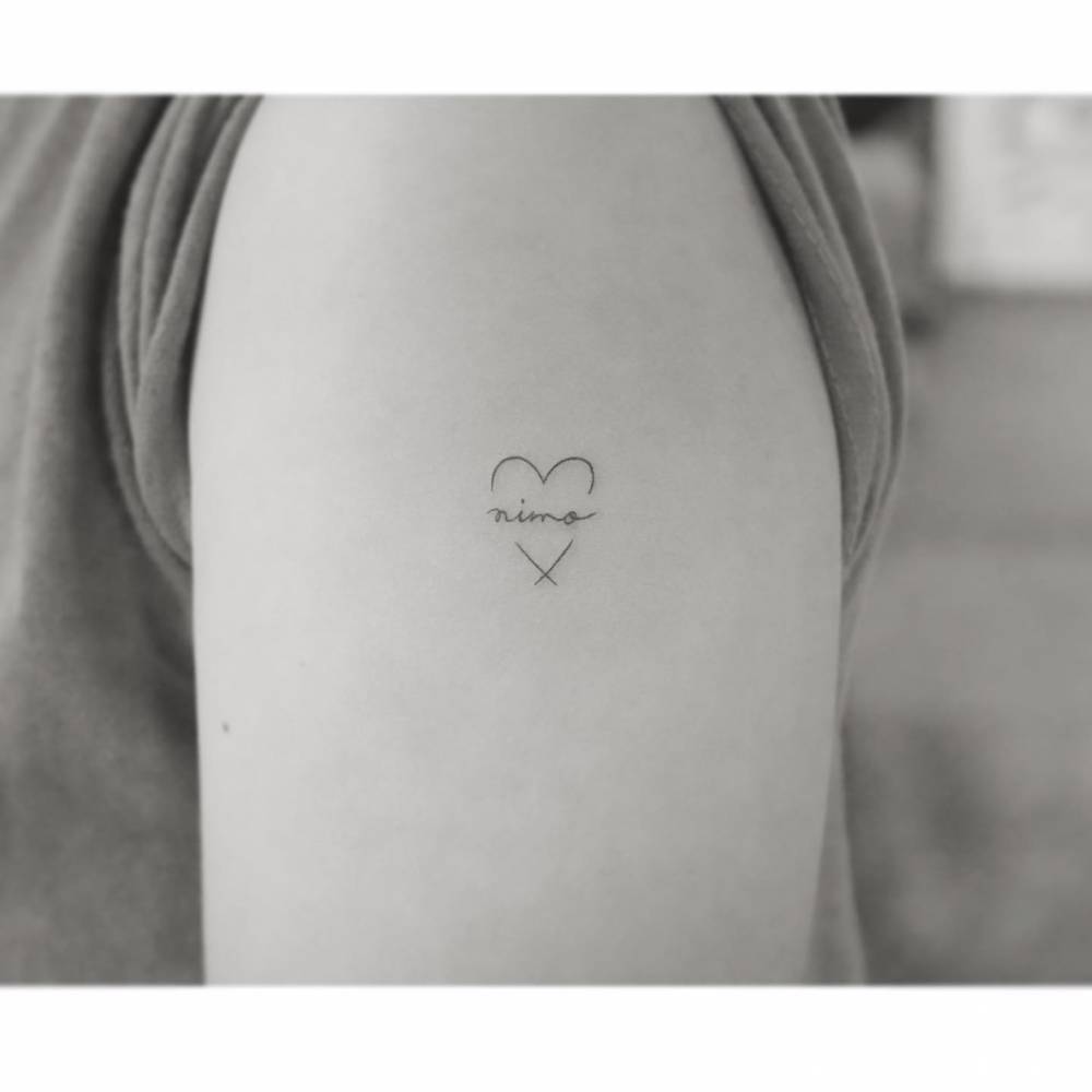 Heart and banner tattoo in minimalistic style located on the upper arm.