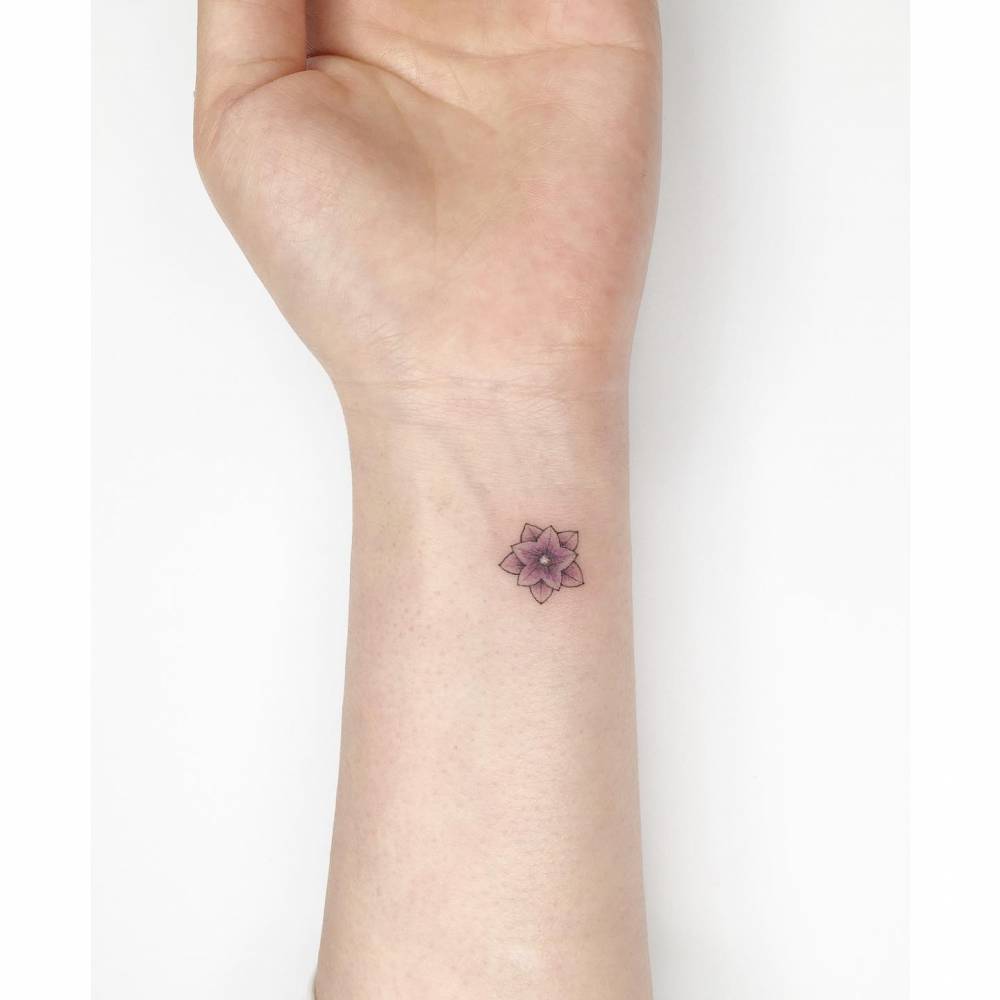 Flower tattoo in illustrative style located on the wrist.