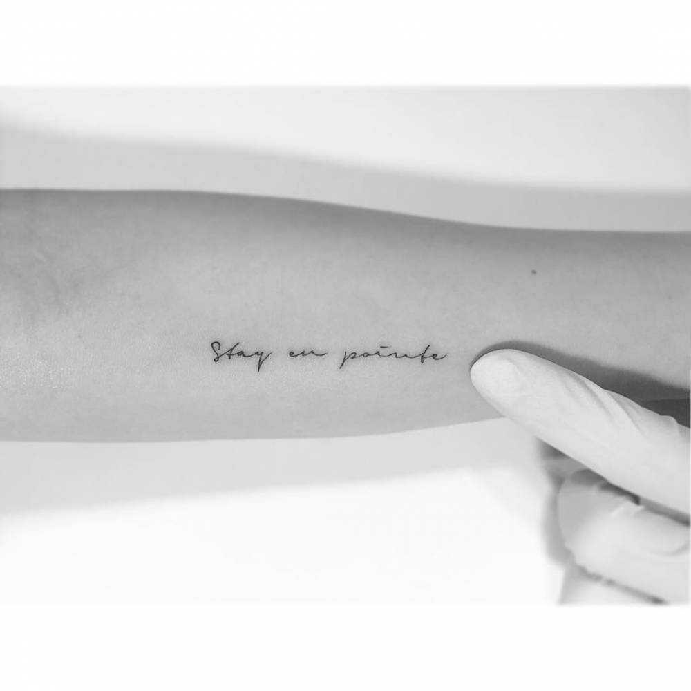 "Stay en pointe" lettering tattoo located on the inner forearm.