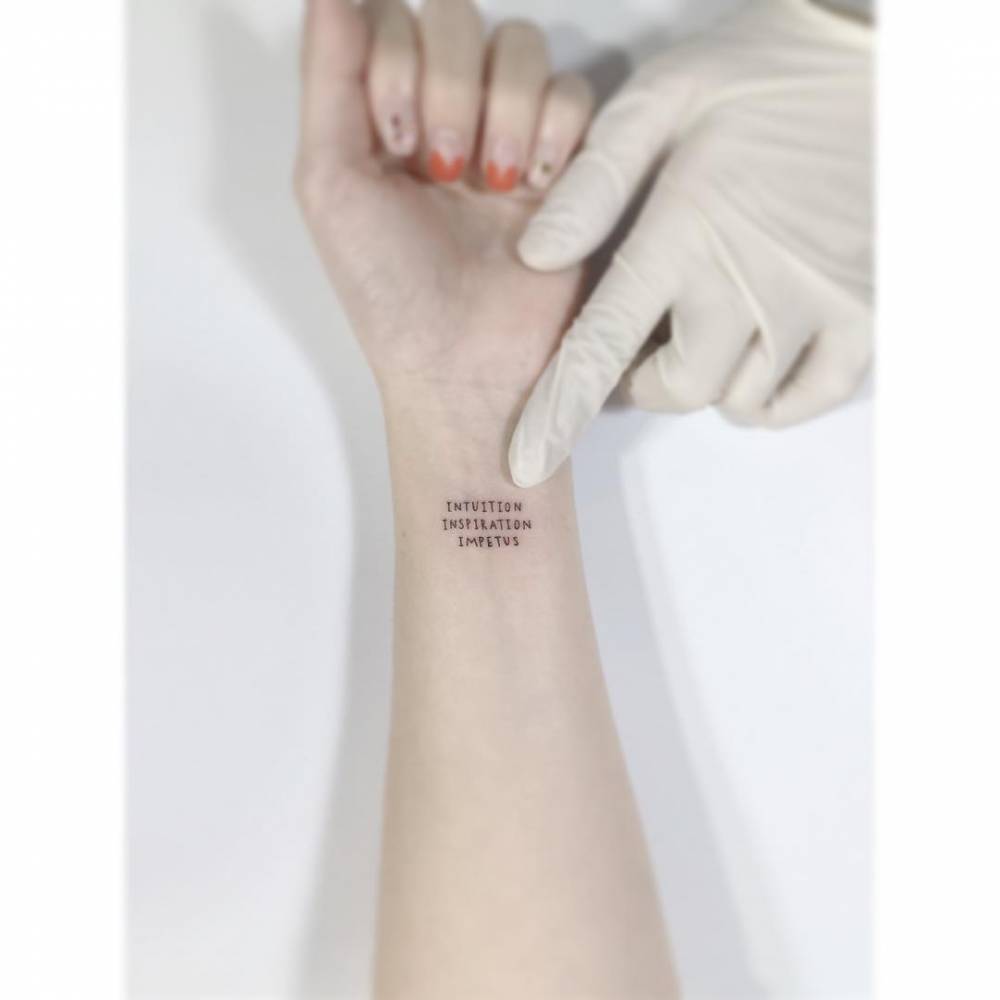 Words "intuition, inspiration and impetus" tattooed on the wrist.