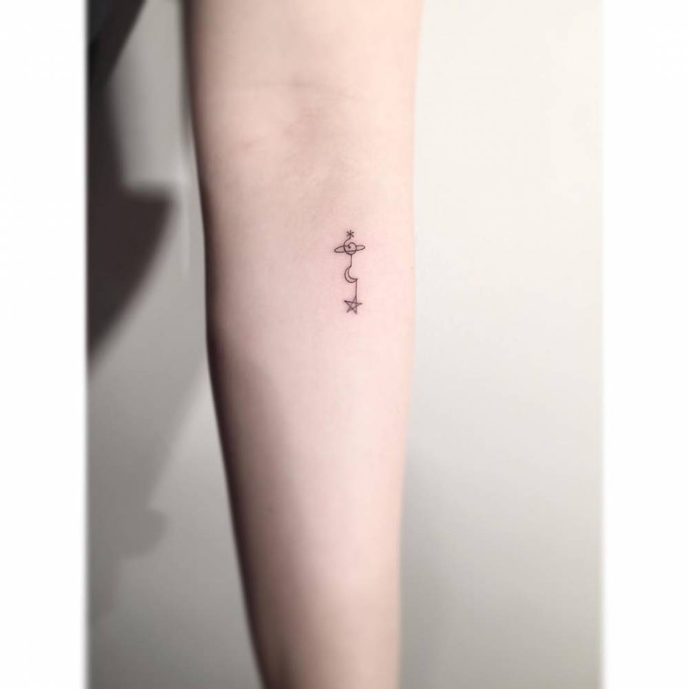 Minimalistic style Saturn, moon and star tattoo located on the inner forearm.