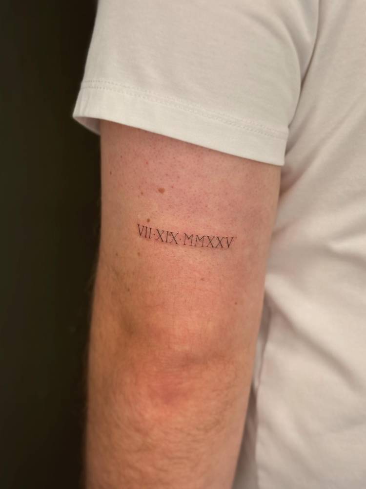 Date in roman numerals tattooed on the tricep.