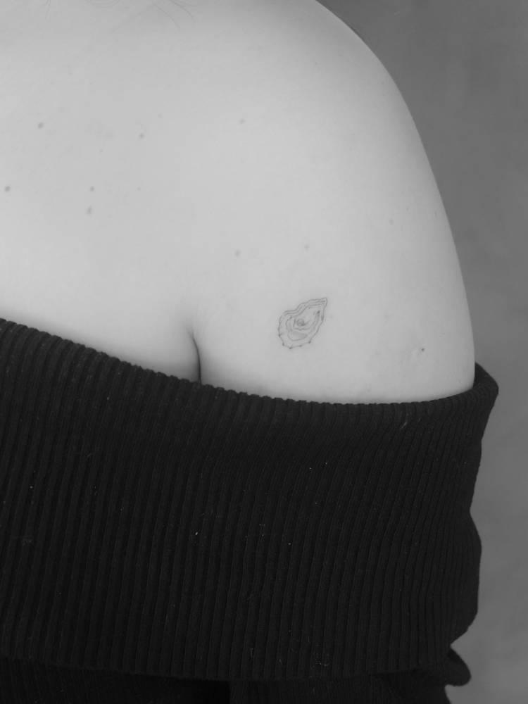 Little oyster tattoo in fine line style located on the shoulder.