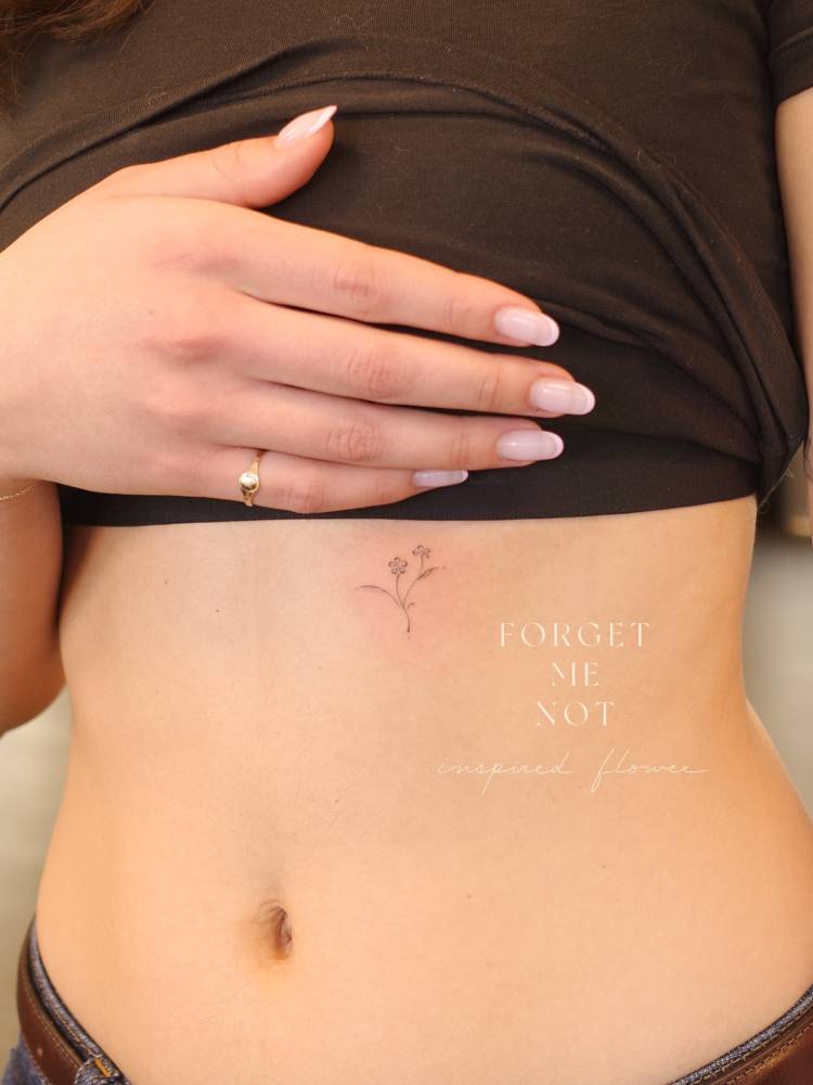 Forget-me-not flowers tattooed on the rib, done in fine line style.