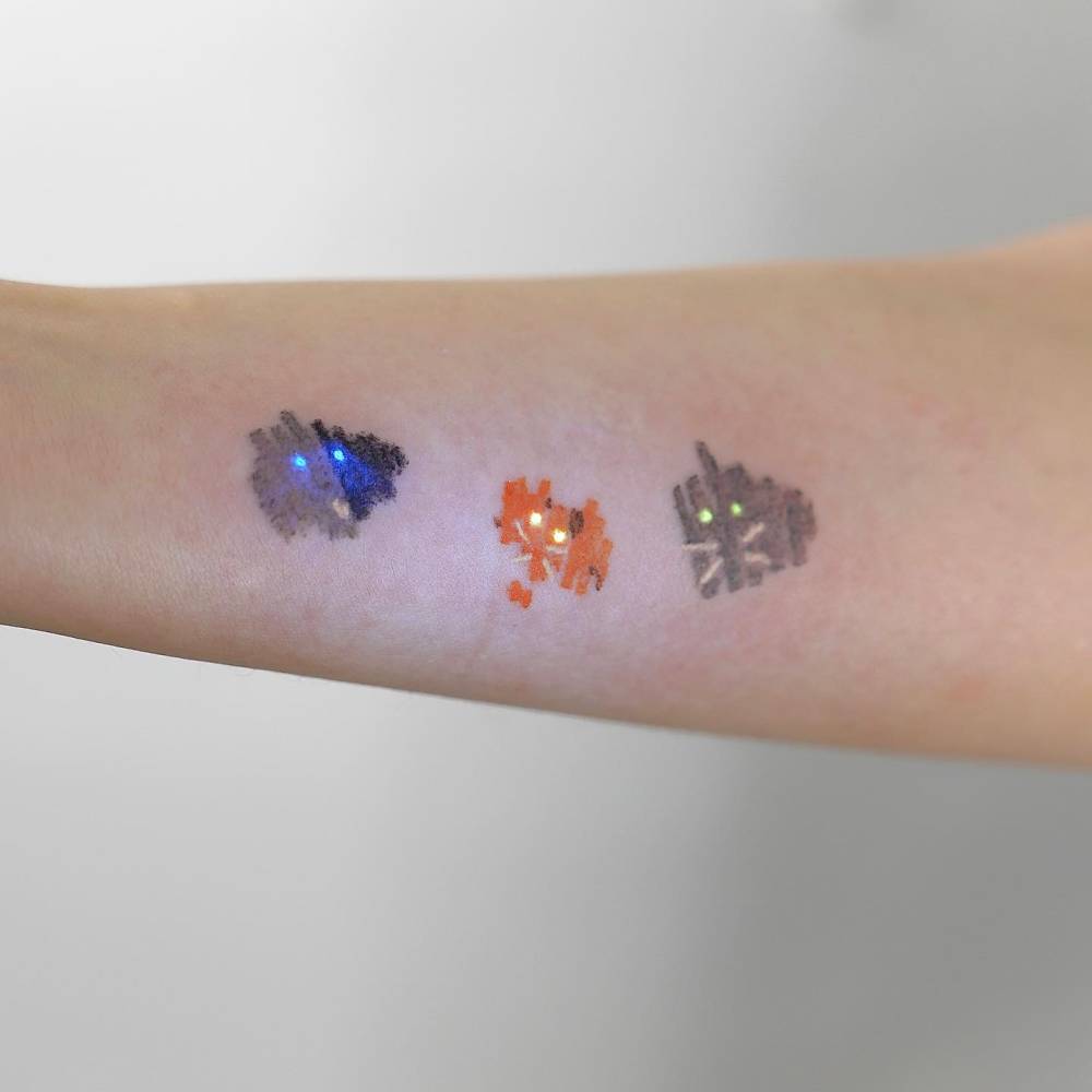 Abstract cats tattooed on the inner forearm.