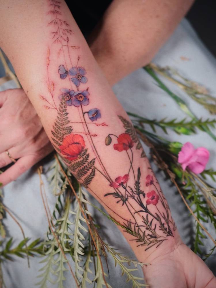Floral collection tattooed on the inner forearm, watercolor style.