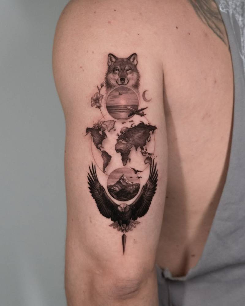 Graphic style wolf head, world map and eagle tattoo located on the tricep.