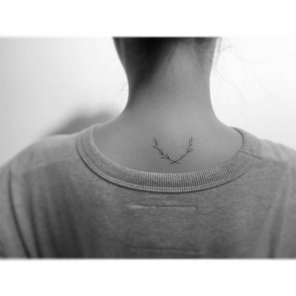 Laurel branch wreath tattooed on the upper back, minimalistic style.