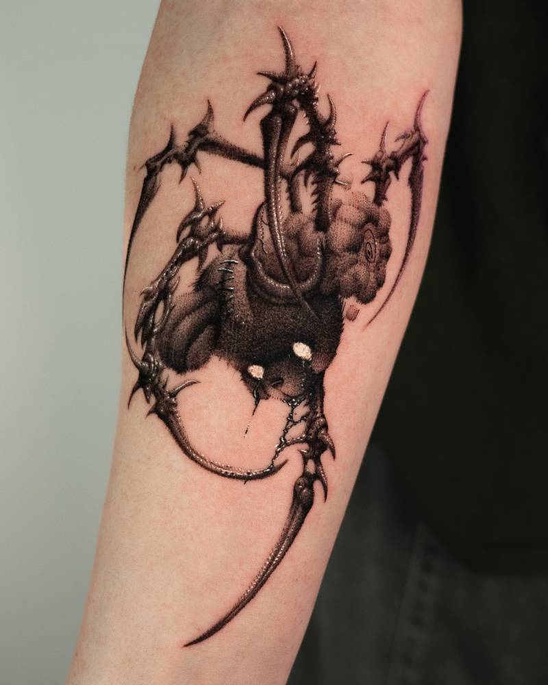 Monstrous teddy bear tattoo located on the inner forearm.