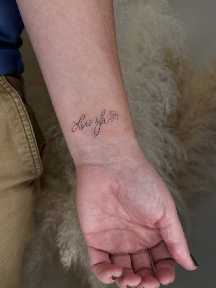 "Love ya" lettering tattoo located on the wrist.