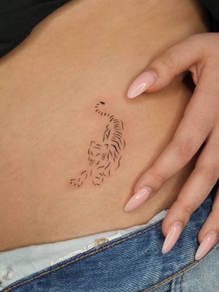 Fine line style tiger tattoo located on the hip.