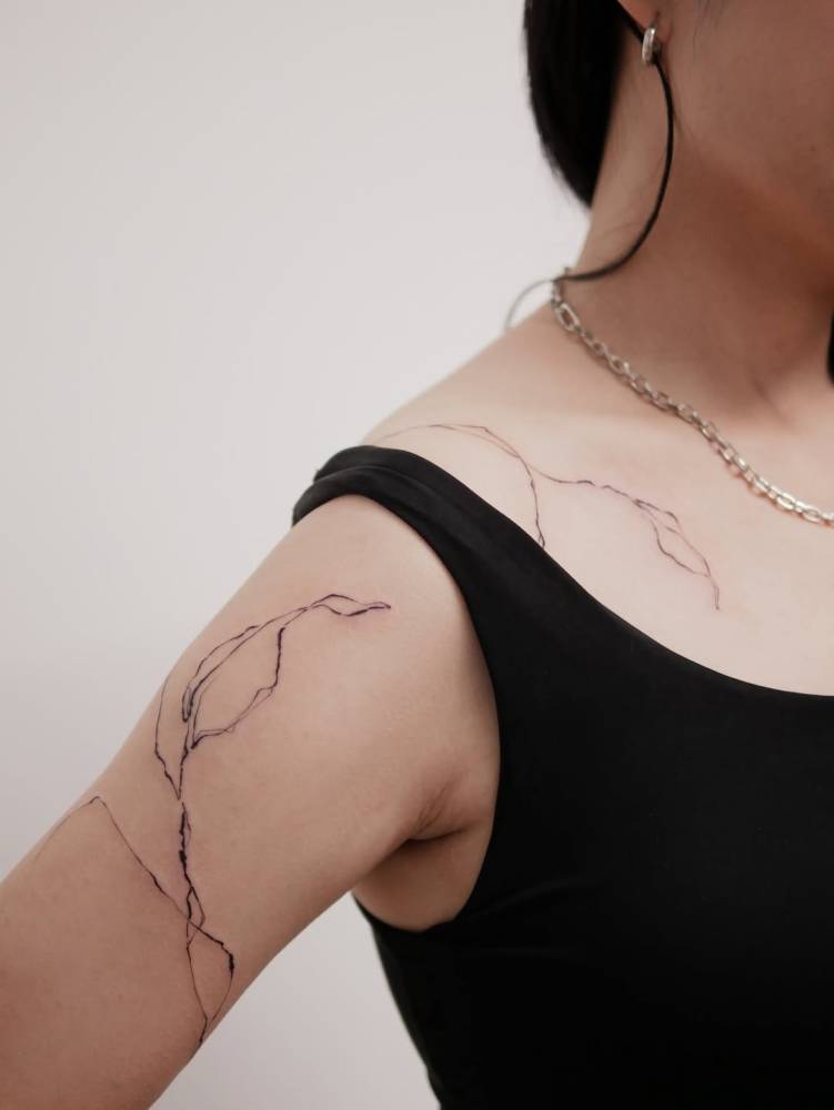 Leaves tattoo located on the upper arm and shoulder.