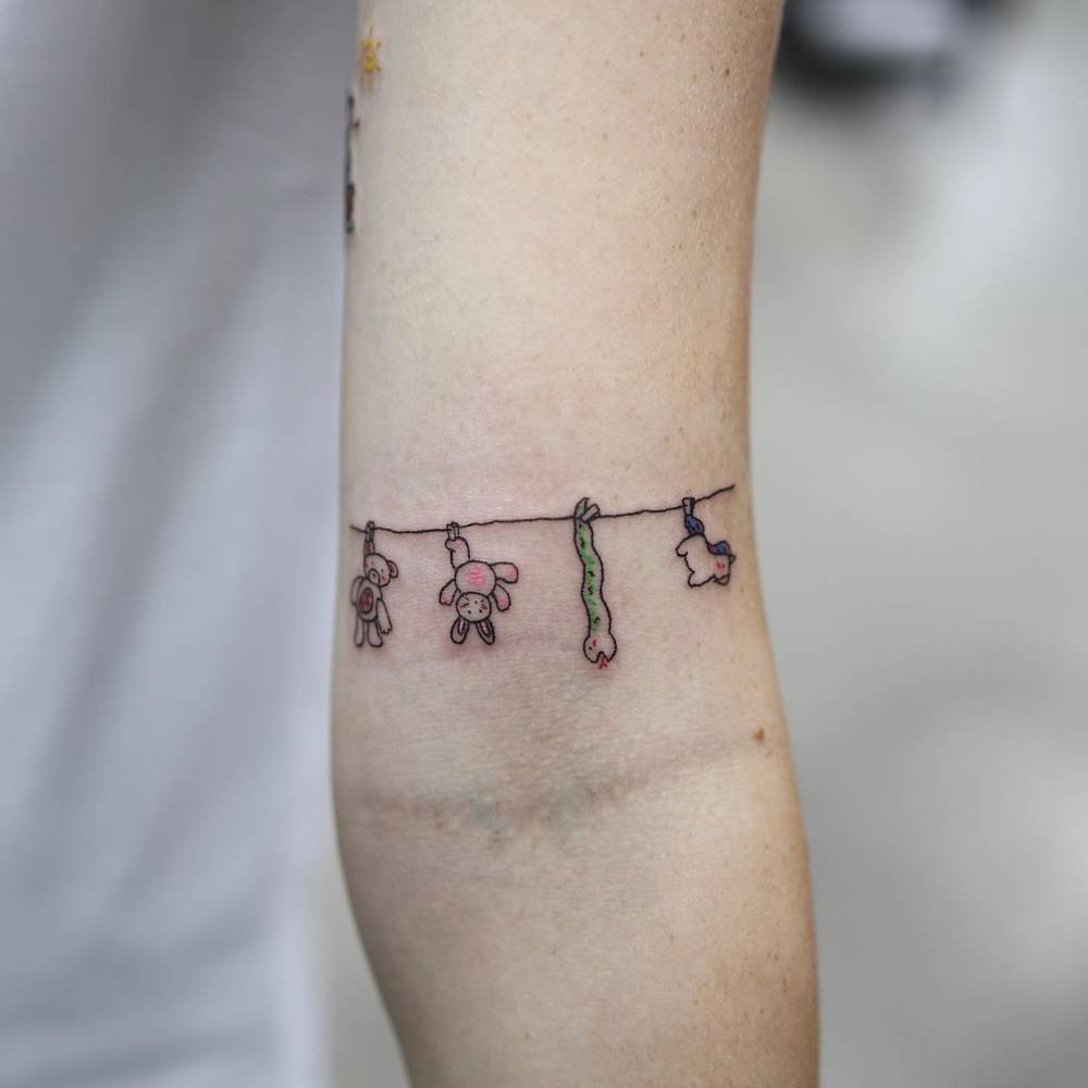 Clothes line with toys hanging tattooed on the bicep.