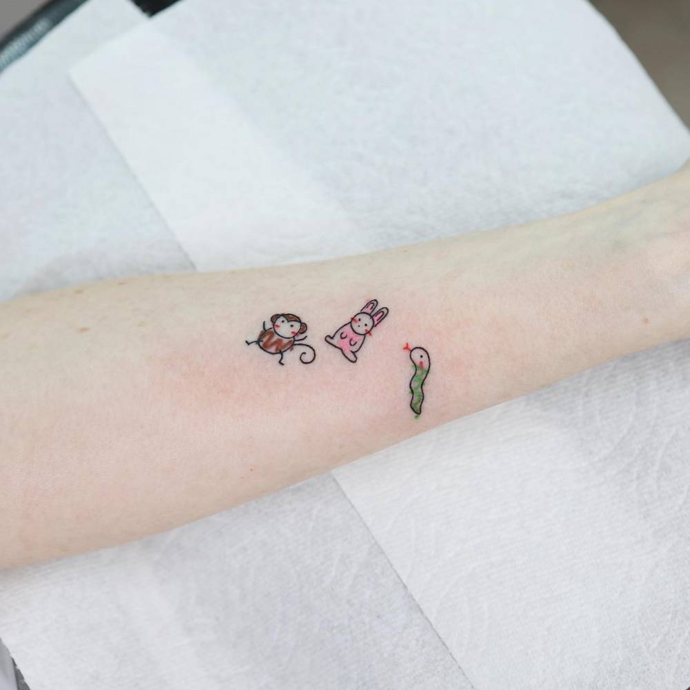 Monkey, bunny and snake tattoo located on the inner forearm, cartoon style.