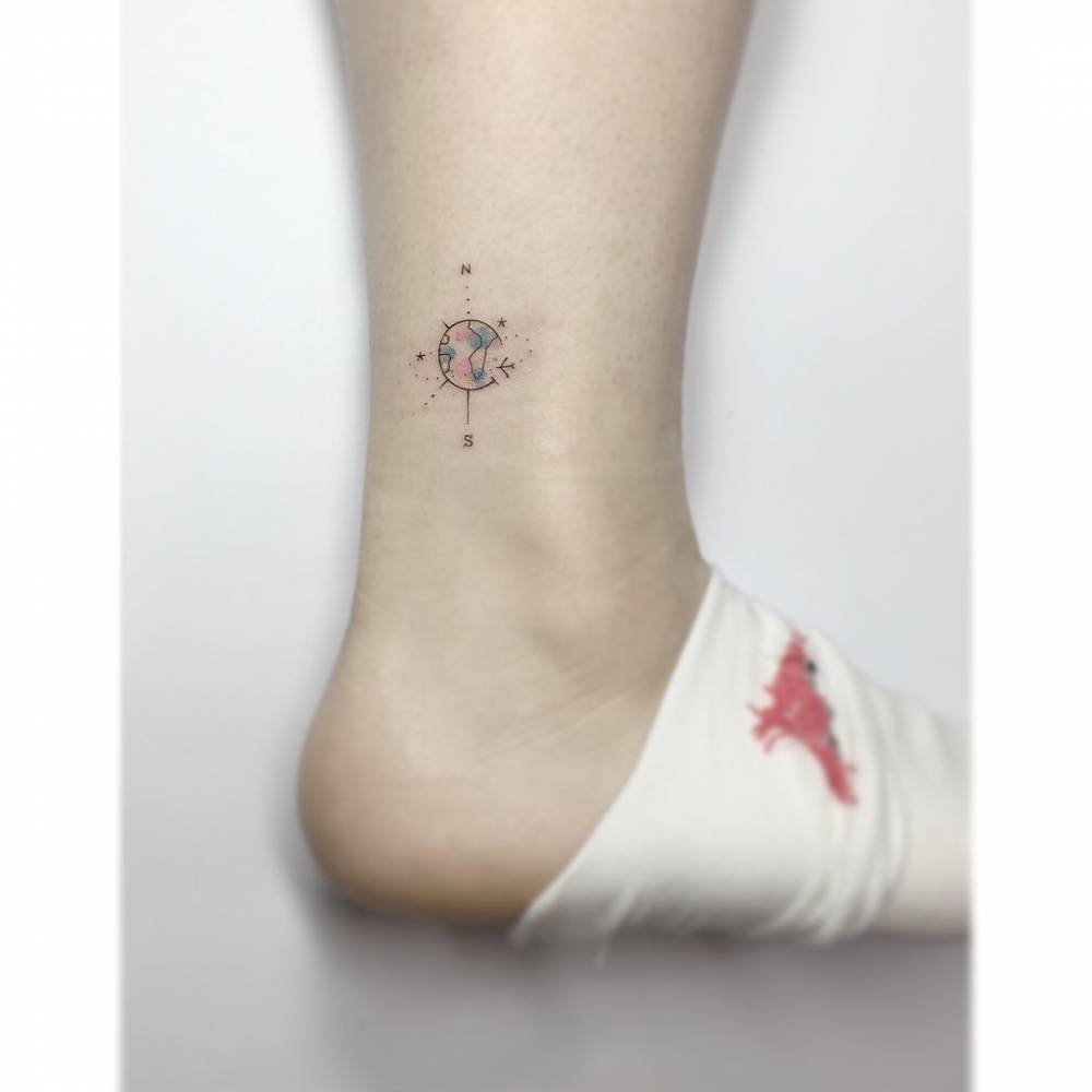 Compass rose tattoo in illustrative style located on the ankle.