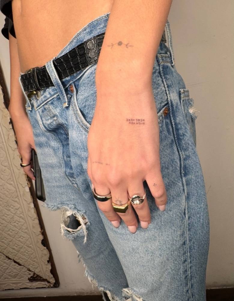 Tiny lettering tattoo that says "wish you were here" located on the hand.