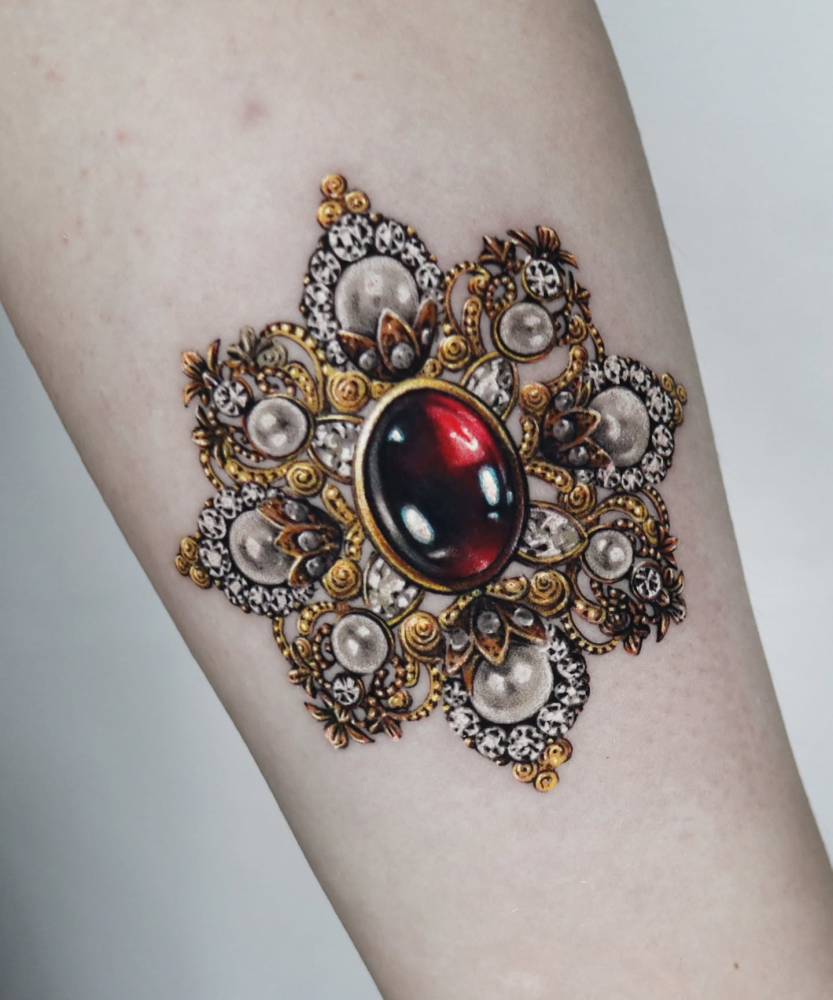 Brooch tattoo in micro-realistic style located on the inner forearm.
