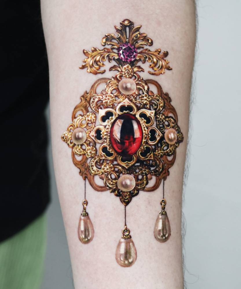 Brooch tattoo in realistic style done on the inner forearm.